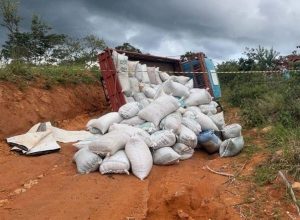 Caminhão carregado com sacas de café tomba e passageiro morre preso às ferragens