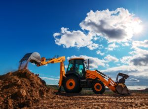 Wheel loader excavator with field background during earthmoving work, construction building
